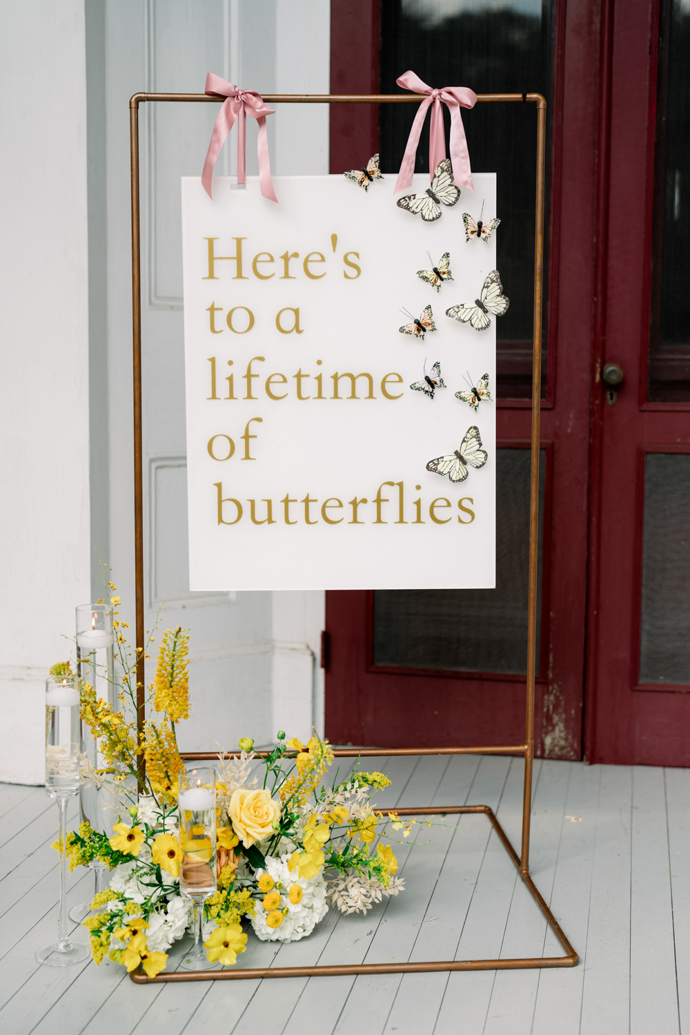 acrylic sign for wedding with gold lettering reading "Here's to a lifetime of butterflies"