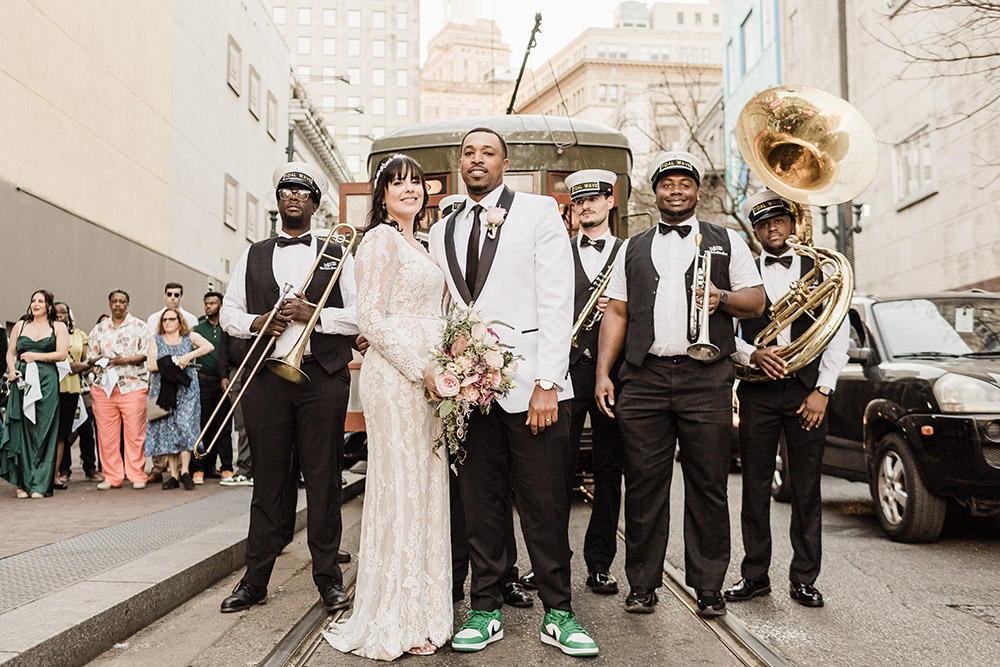 The bride and groom pose in front of the streetcar with their brass band, Tidal Wave Brass Band.