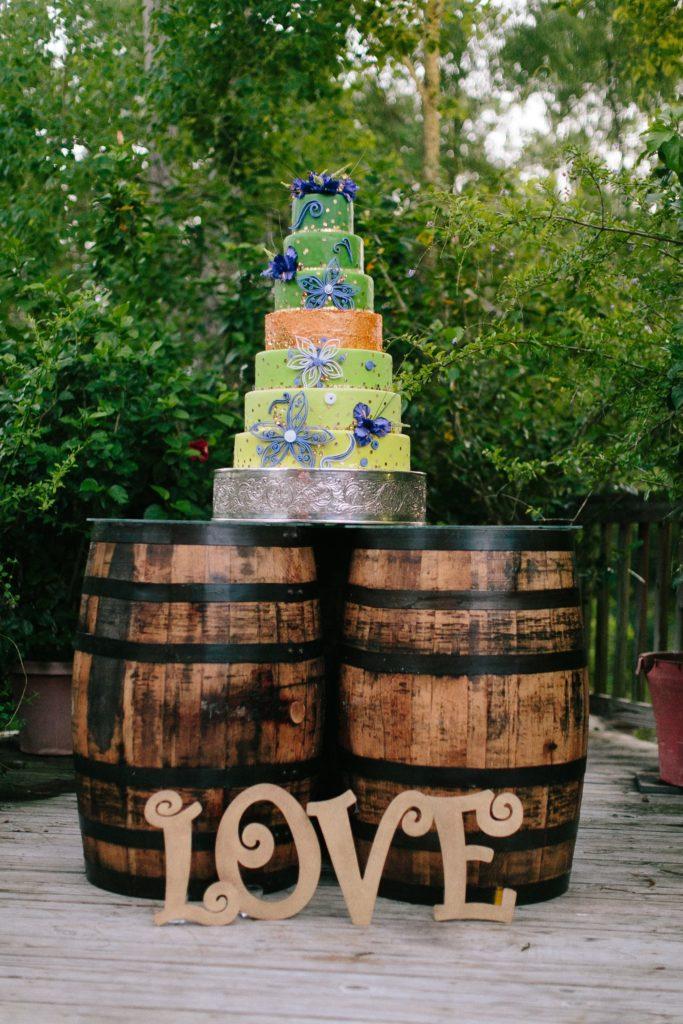 A fanciful 7-tier wedding cake sits atop a wine barrel cake table. 