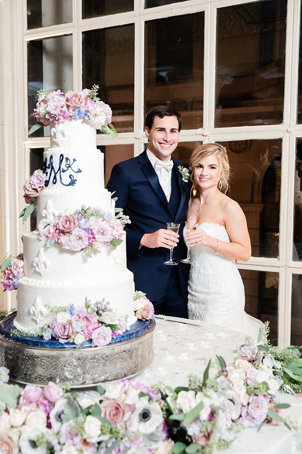 Abbie and Kevin’s stunning 5-tier wedding cake by Gambino’s Bakery featured a fleur de lis motif and their monogram in royal blue icing. Fresh flowers in soft pastel tones embellished the cake and cake table.