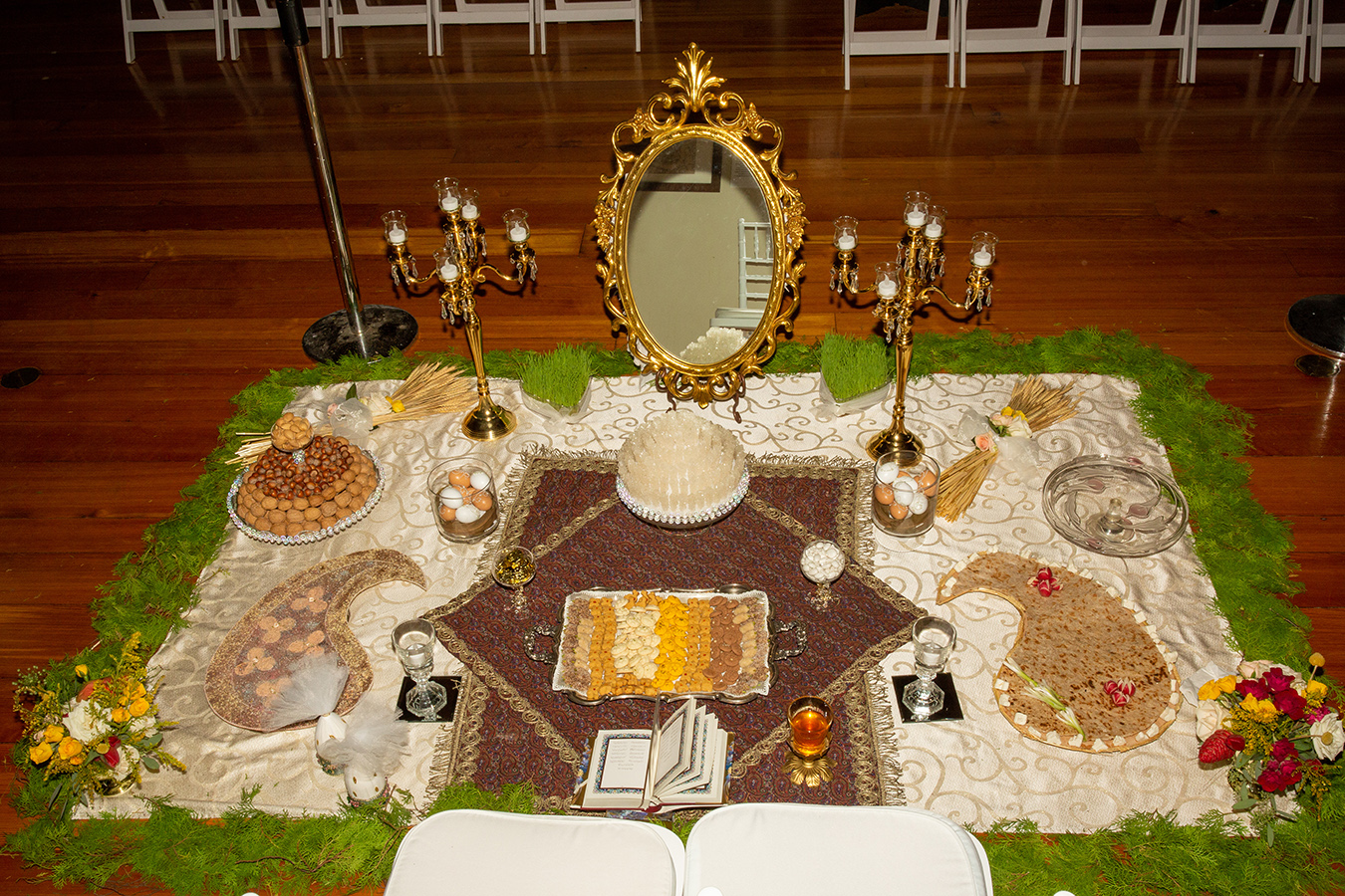 The "Sofreh Aghd" included Rue Seeds, Traditional Pastries, Mirror and two candelabras, Bread, feta cheese, and greens, Decorated eggs, almonds, walnuts and hazelnuts, Fruits: pomegranates, grapes, apples; Gold Coins; Hafez's Divan, and an Antique Paisley Rug.