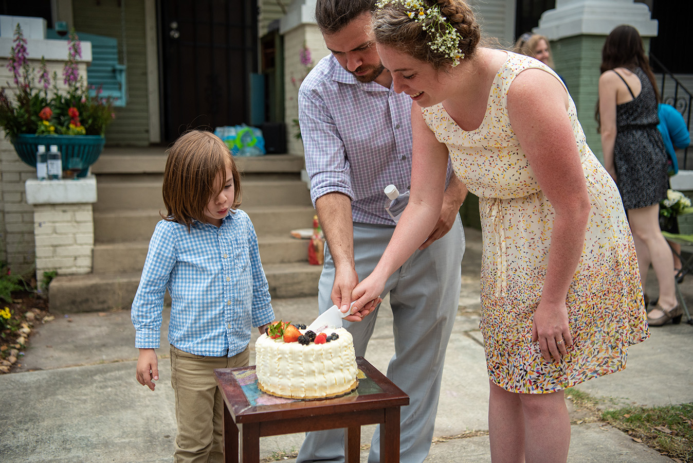 Elizabeth and Greg cut their Berry Chantilly wedding cake from Bywater Bakery with their son Frank watching.