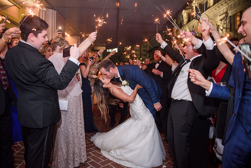 bride and groom kissing as guests wave sparklers