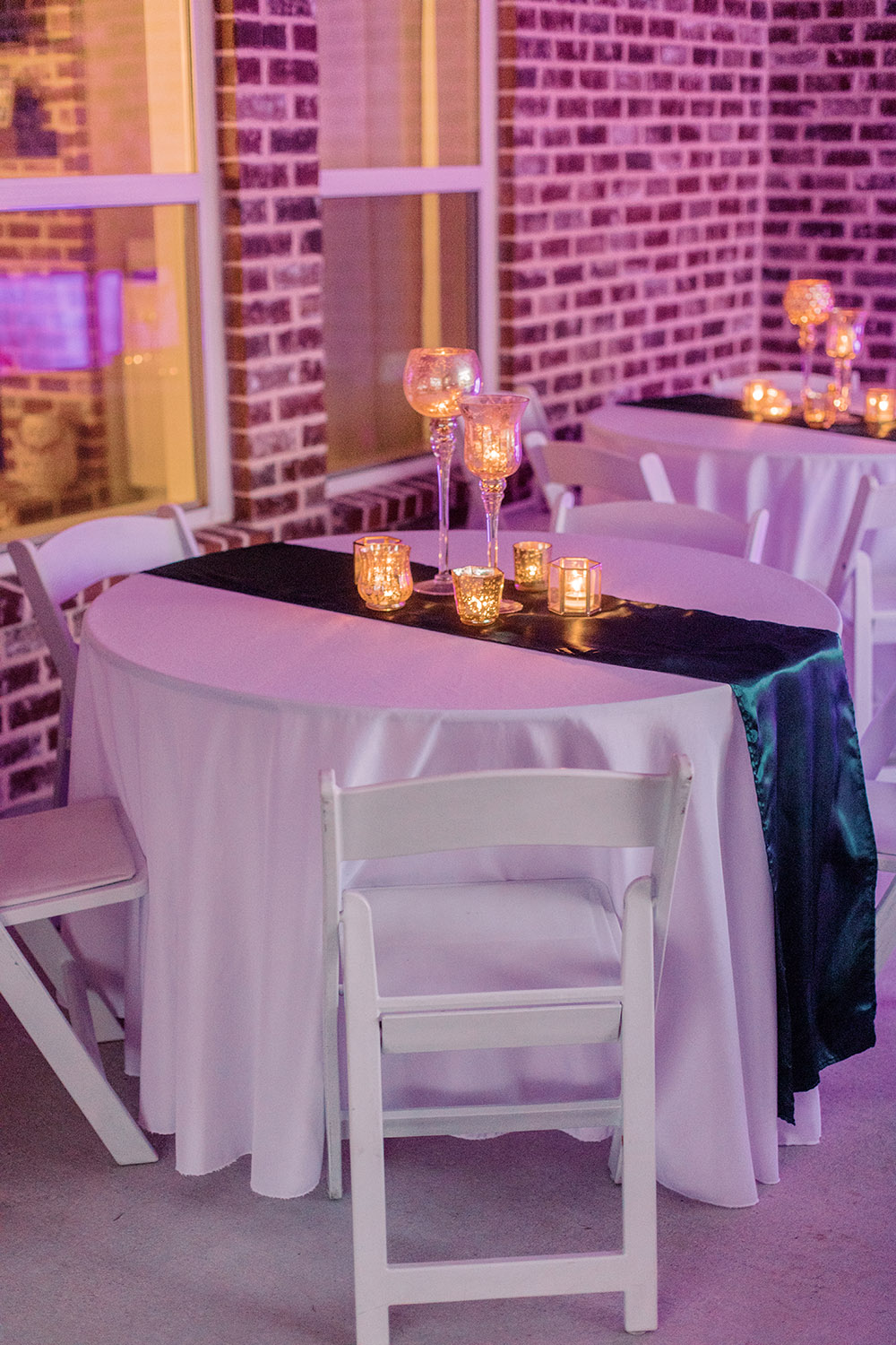 Reception tables with emerald satin runners and candles. Photo: Ashley Kristen Photography
