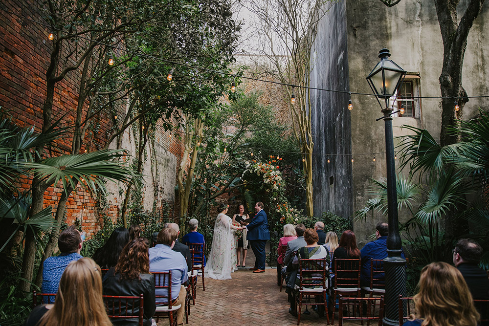 Del and Peter exchange vows under a floral arch in the Pharmacy Museum Courtyard. Photo: Ashley Biltz