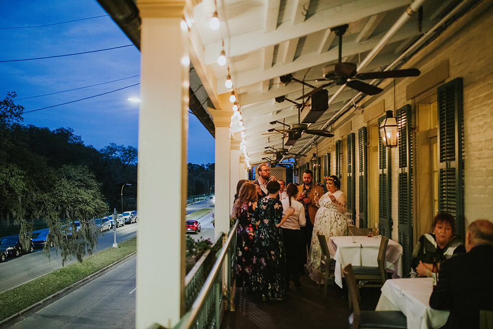 The wedding guests enjoy cocktails on the balcony at Ralph's on the Park overlooking New Orleans' historic City Park. Photo: Ashley Biltz
