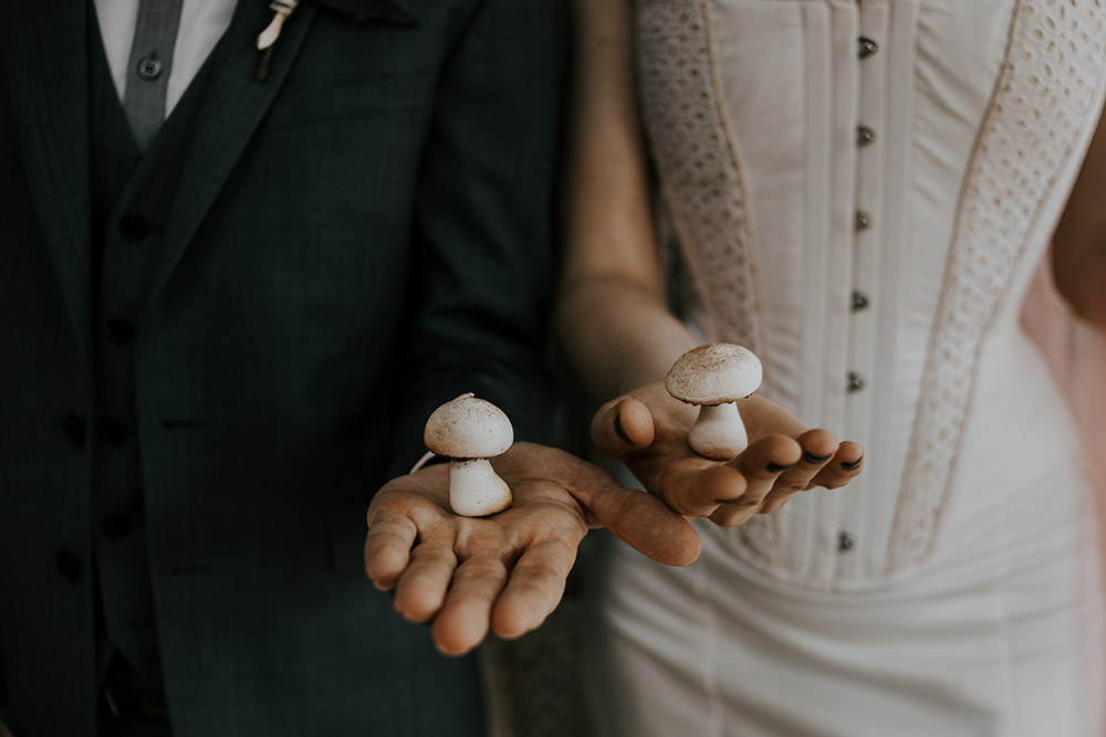 Bride and groom each hold a mushroom meringue