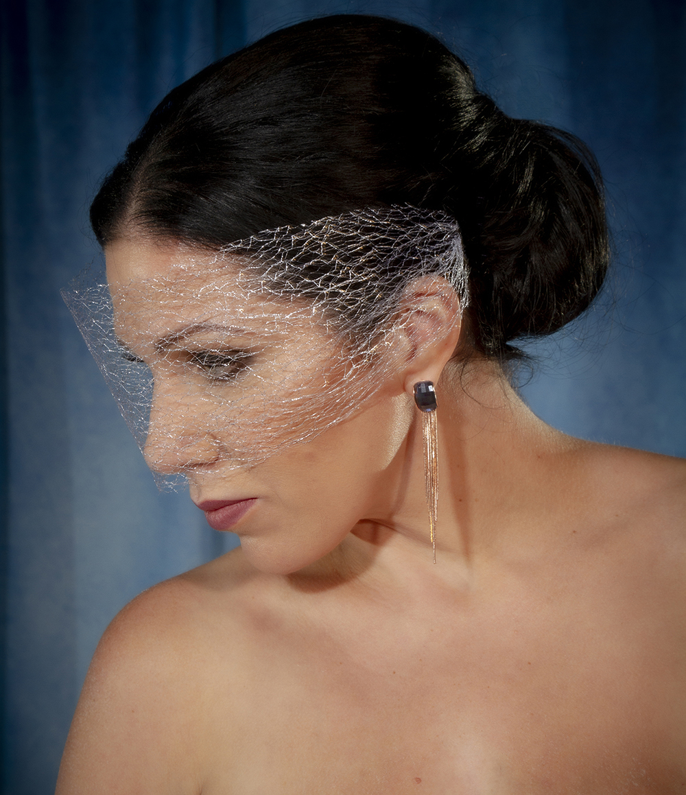 A silver net birdcage veil and blue rhinestone drop earrings with rose gold waterfall tassel complete her look.