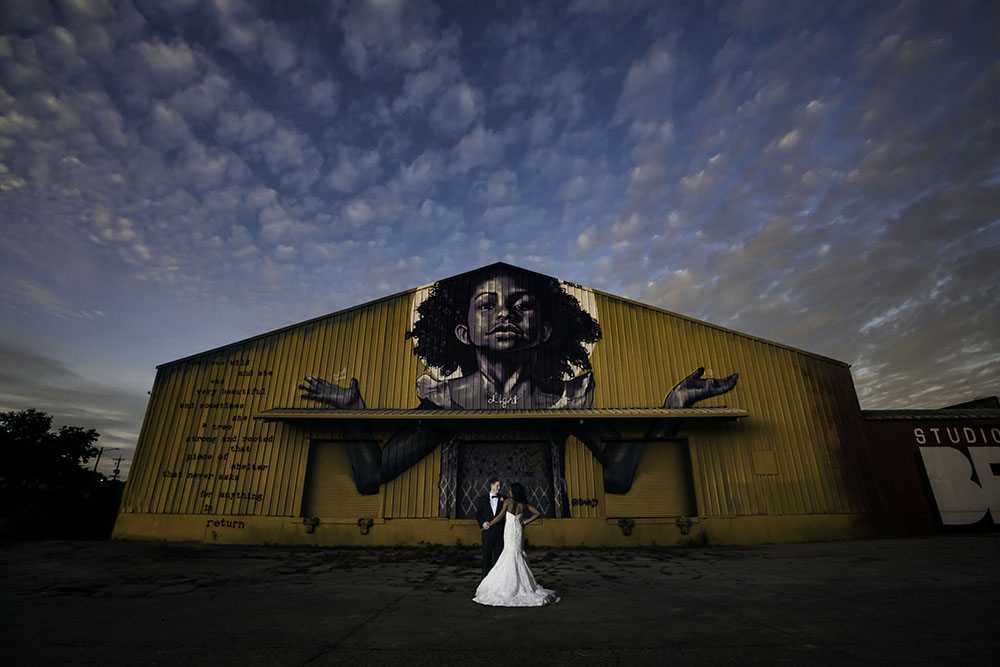 Bride and Groom posing in front of Bywater warehouse with mural by Brandon Bmike Odums | Brian Jarreau Photography
