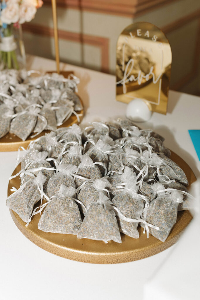 Wedding favors displayed on a tray, featuring small organza bags filled with dried lavender at the reception.