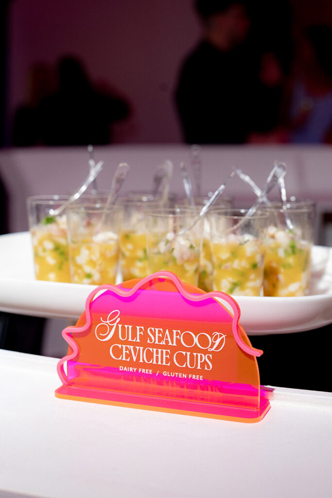 Neon pink sign reading “Gulf Seafood Ceviche Cups” displayed in front of individual ceviche cups at a wedding reception.