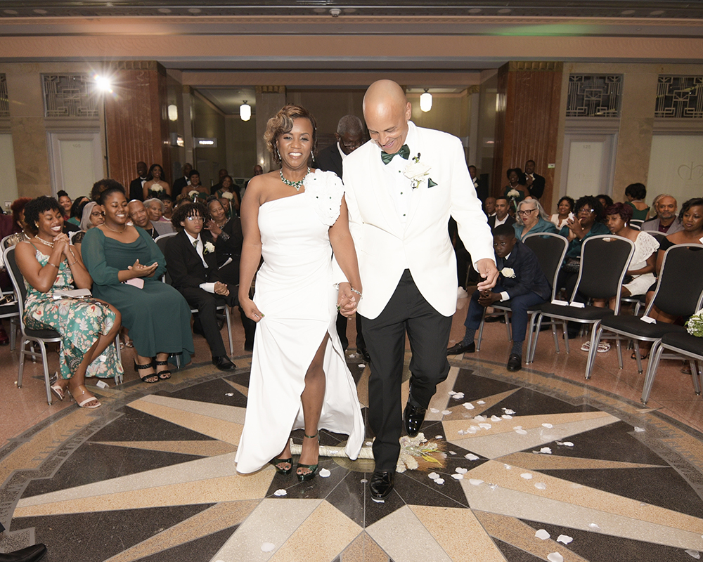 Bride and groom walk hand in hand down the aisle as guests applaud following their ceremony.