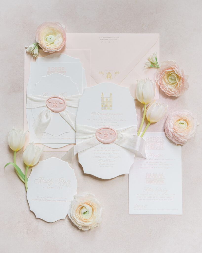 Blush and ivory wedding invitation suite with wax seals and soft florals styled on a neutral background.