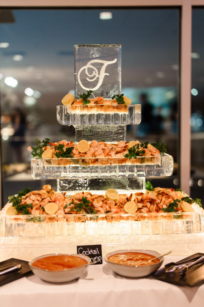Tiered ice sculpture shrimp display with fresh seafood, lemon garnish, and cocktail sauce at the reception.