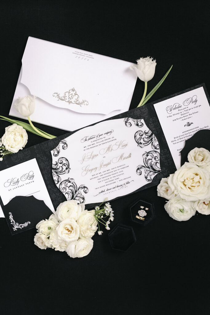 Elegant black and white wedding invitation suite with florals, rings, and formal calligraphy styling.