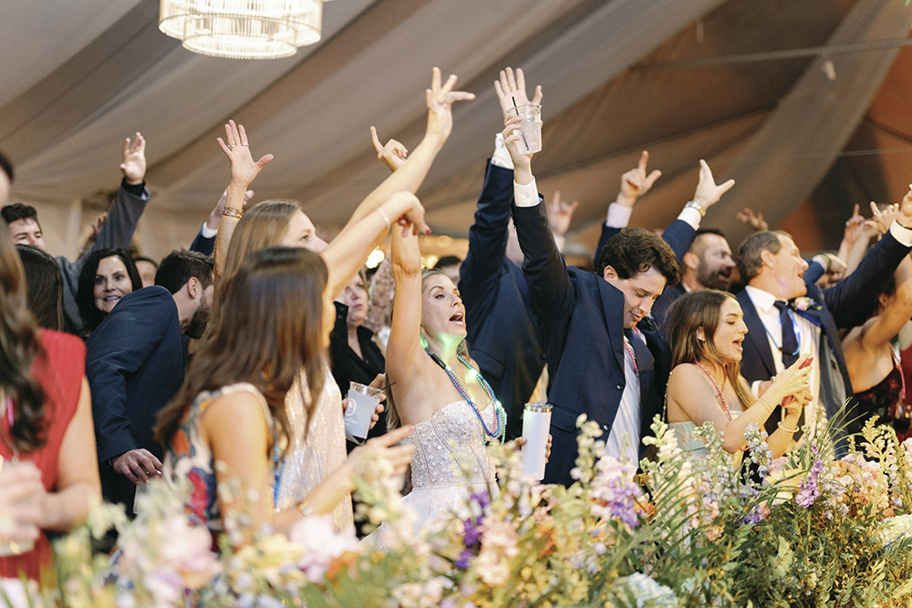 Guests dancing and celebrating under the clear-top tent as the band performs, capturing a lively wedding reception moment.