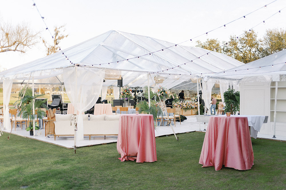 Reception lounge seating with white sofas, pastel accent pillows, and a glass coffee table topped with a floral arrangement.
