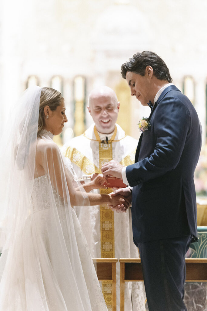 Bride and groom exchanging rings at the altar as the officiant looks on during a traditional church ceremony.
