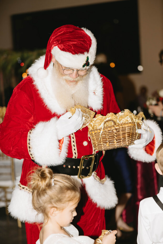 Santa Claus hands out gold favors to children during the reception, adding a festive holiday touch.