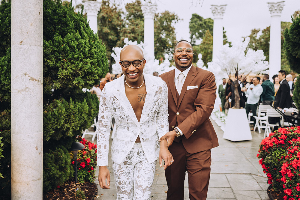 Newlywed couple walking down the aisle smiling after their ceremony as guests celebrate around them.