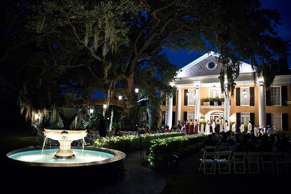 Outdoor evening wedding ceremony at historic Southern estate in Mobile, Alabama with fountain and oak trees
