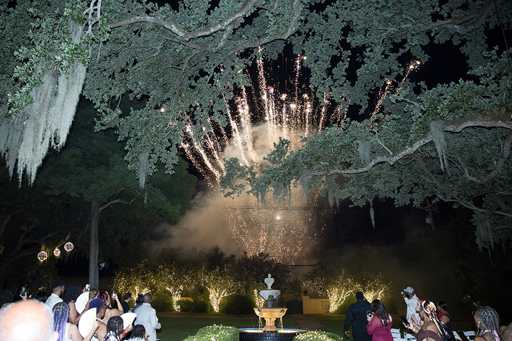 Wedding fireworks display over oak trees and garden reception in Mobile, Alabama at night