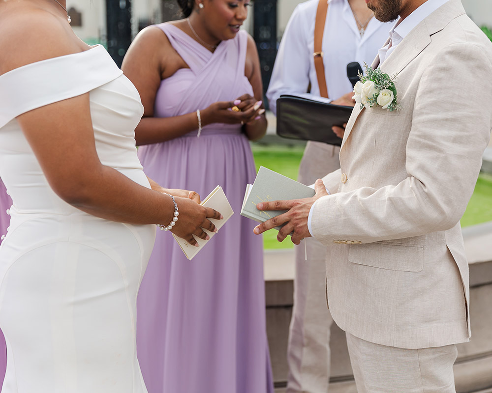 Close-up of bride and groom exchanging vows during outdoor wedding ceremony in New Orleans with bridesmaids in lavender