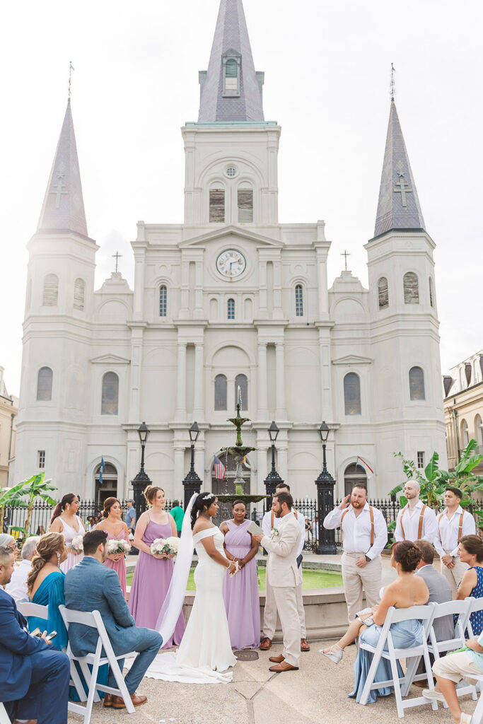 Outdoor wedding ceremony in Jackson Square in New Orleans in front of St. Louis Cathedral with bridal party and guests seated