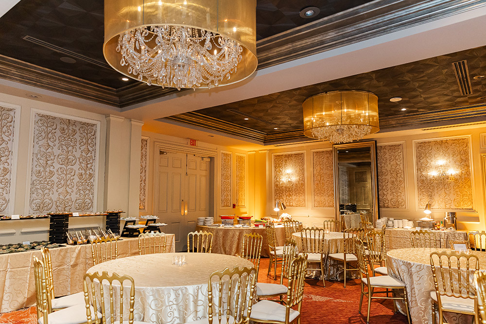 Elegant wedding reception ballroom with gold chairs, chandeliers, and buffet tables set for celebration in New Orleans venue