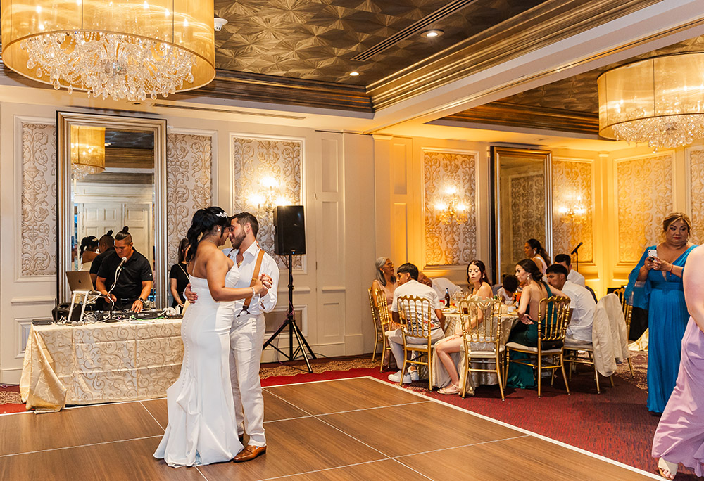 Bride and groom sharing first dance in elegant ballroom reception in New Orleans with guests seated and DJ in background