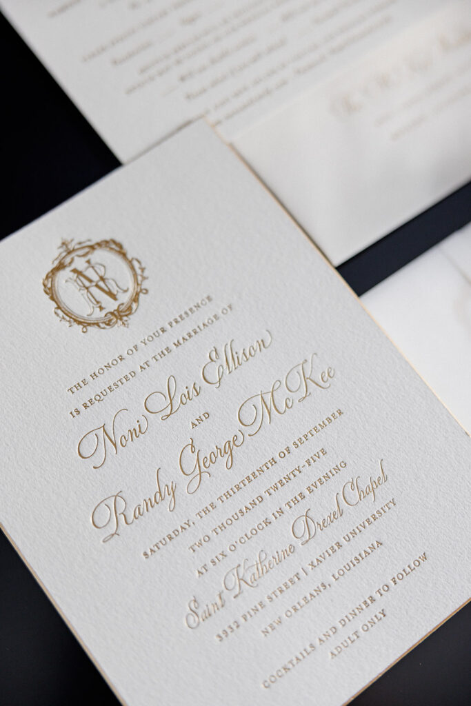 Elegant white and gold wedding invitation suite with monogram crest and formal script calligraphy for New Orleans church wedding