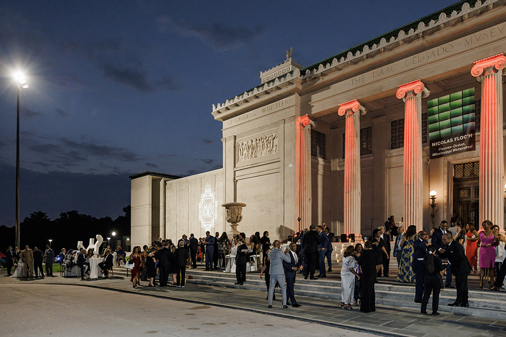 Guests gather outside the illuminated museum entrance during the evening wedding reception celebration.
