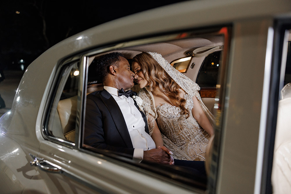 Newlyweds share a quiet romantic moment inside a vintage white car at the end of the wedding celebration.