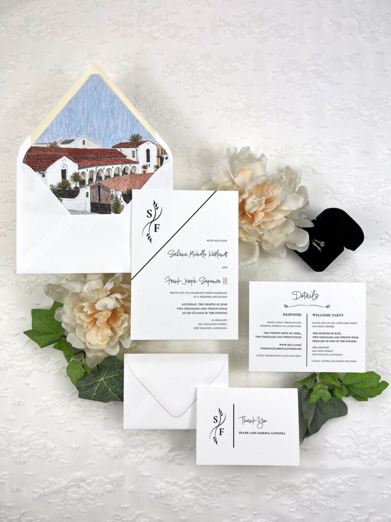 Modern minimalist wedding invitation suite with deckled-edge invitation card, watercolor venue envelope liner, and clean black typography styled with greenery.