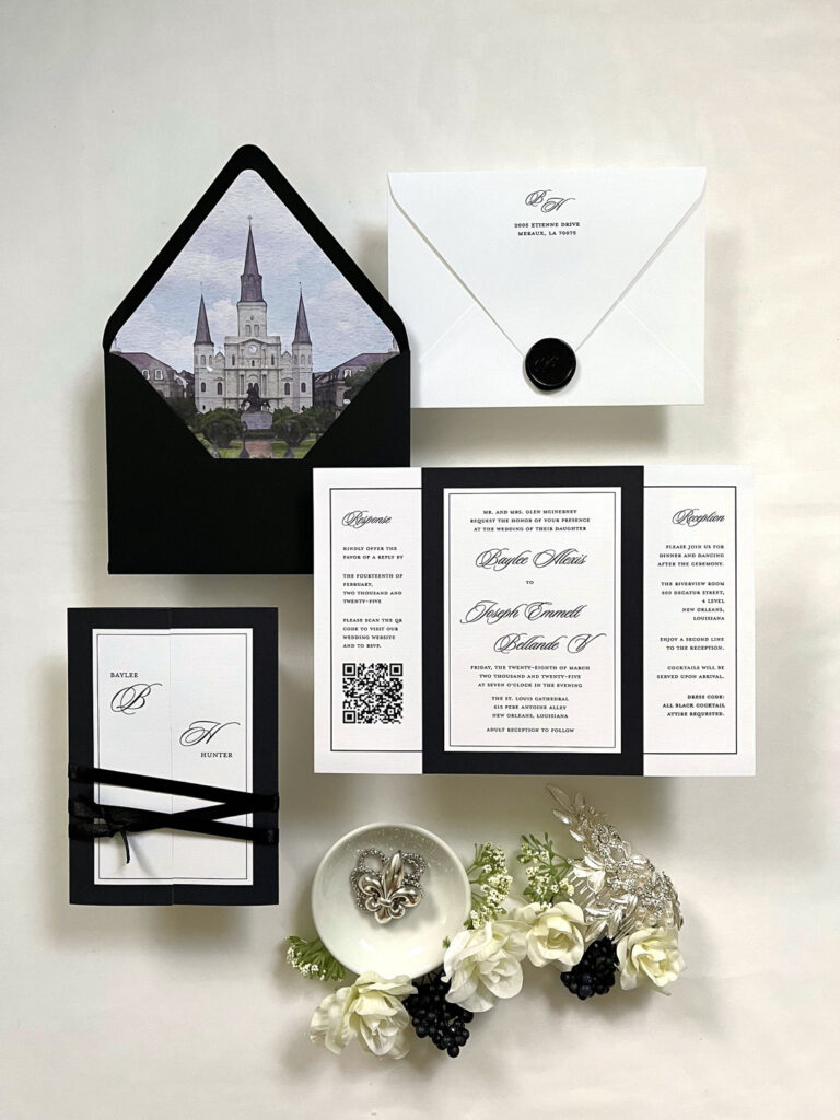 New Orleans-inspired black and white wedding invitation suite with cathedral envelope liner, wax seal details, fleur-de-lis accents, and elegant formal typography.