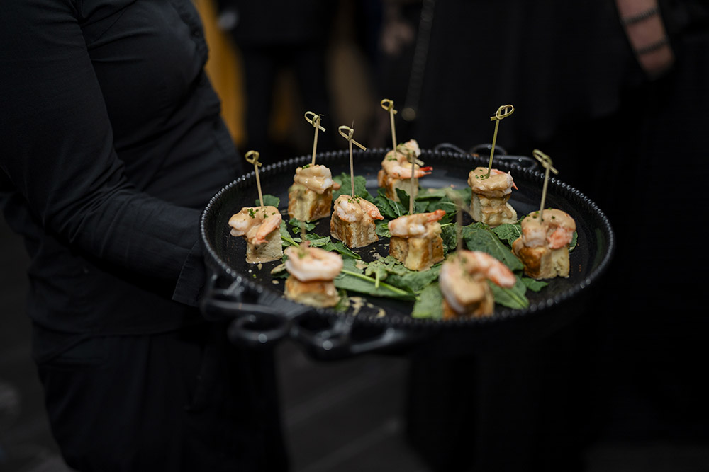 Passed shrimp hors d’oeuvres served on a black tray during cocktail hour at an upscale wedding reception.