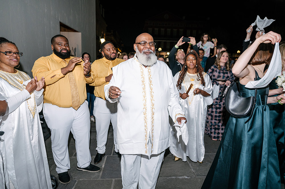 Second line musicians and guests leading a lively nighttime wedding procession through the French Quarter after the ceremony.