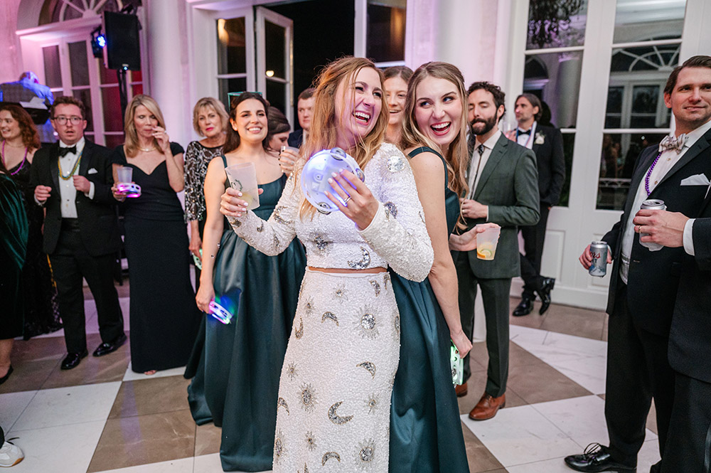 Bride in a sparkling celestial-inspired reception gown dancing with a bridesmaid during the reception as guests smile and watch nearby.
