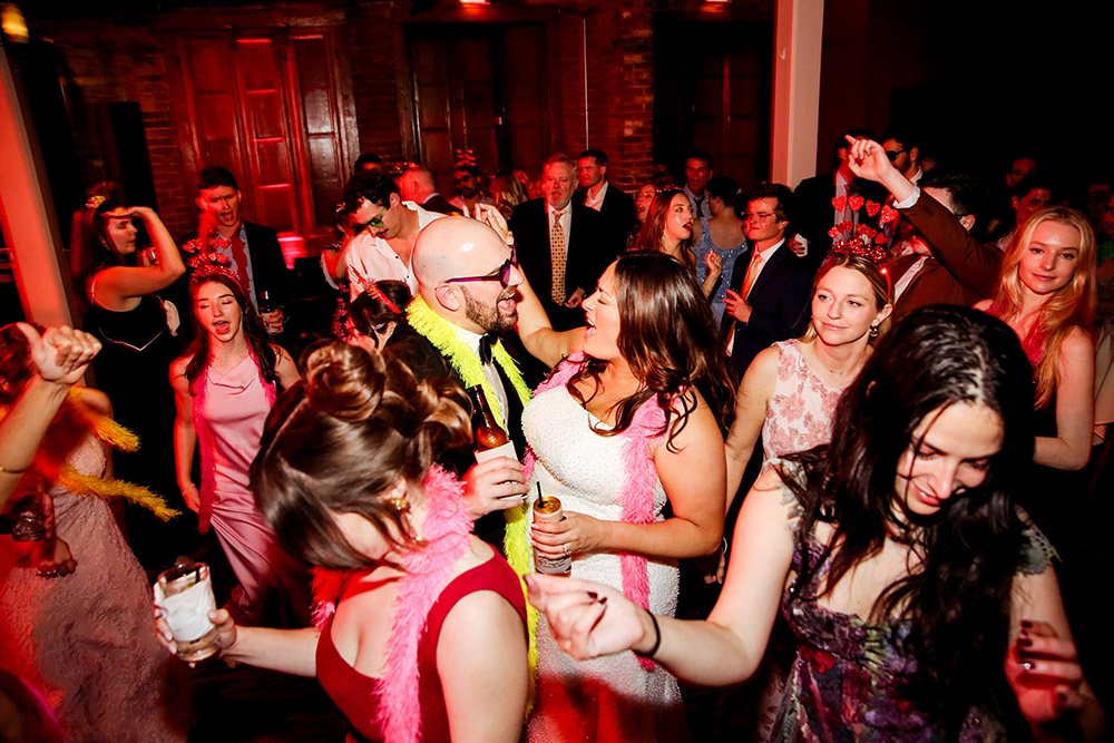 Bride and groom dance together at their lively wedding reception surrounded by guests.