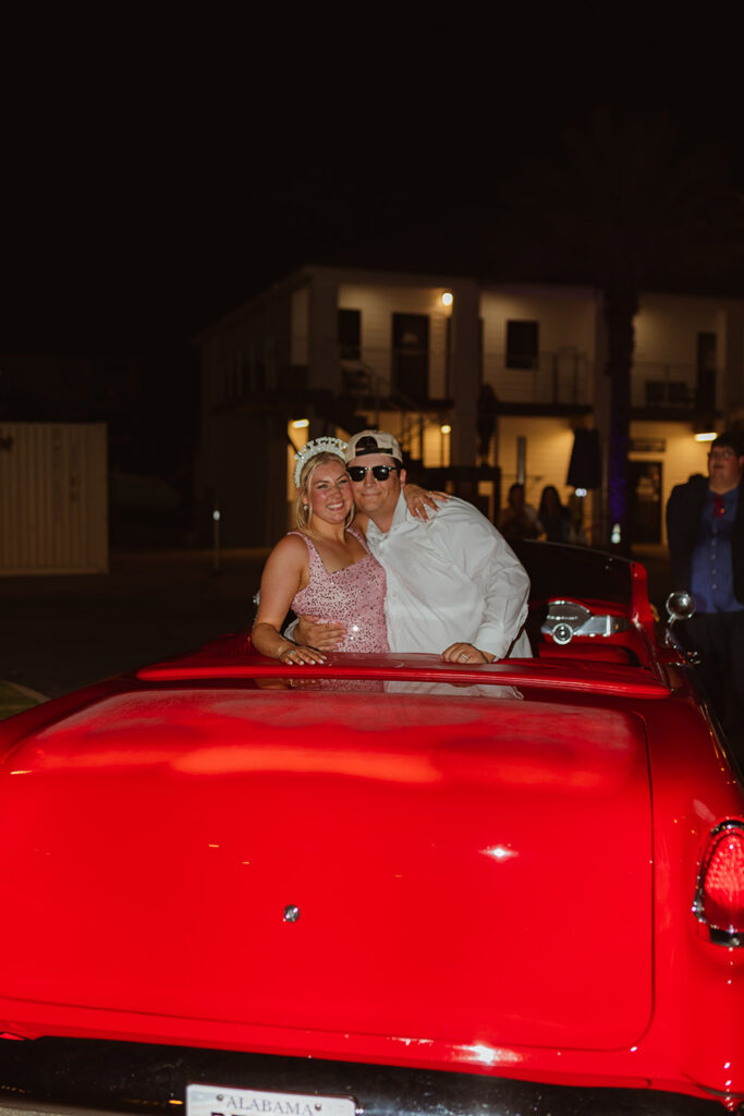 The newlyweds smile from a bright red vintage convertible as they make their grand exit.