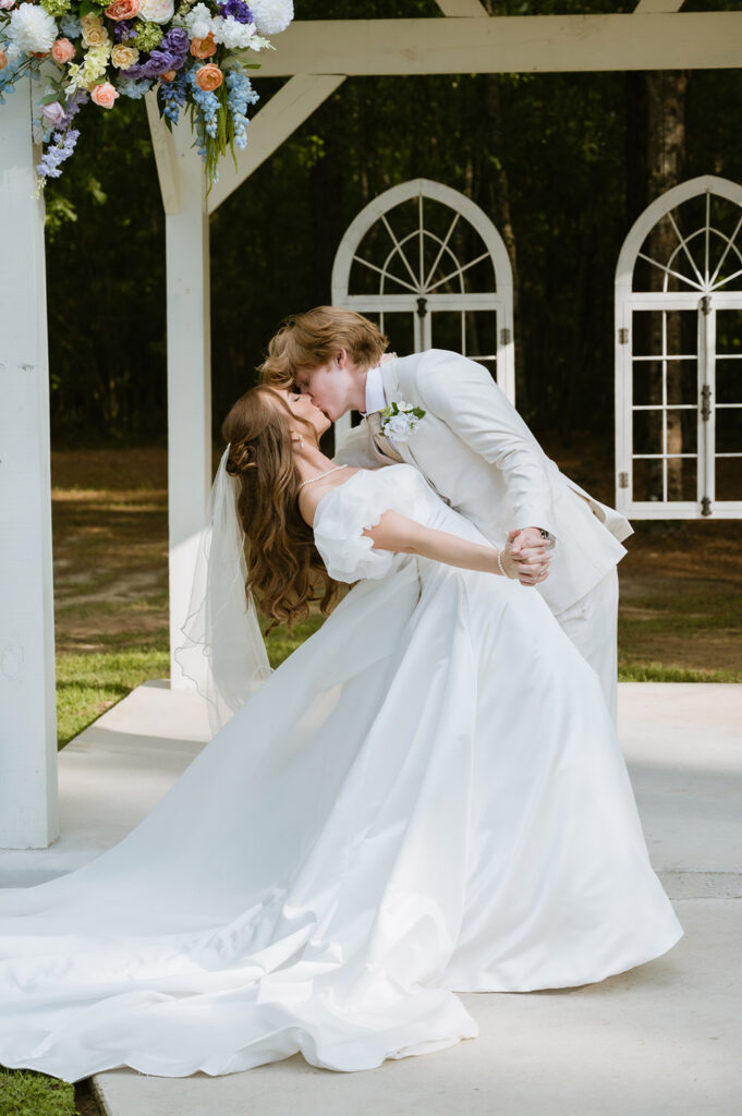 Bride and groom share a kiss beneath the ceremony arbor after exchanging vows.