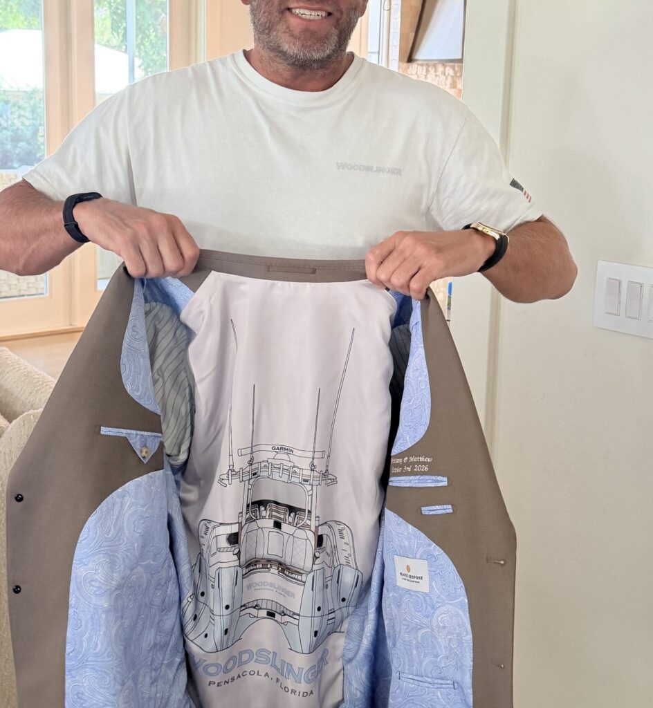 Man opening a brown suit jacket to show a custom fishing boat graphic interior lining by Pearce Bespoke.