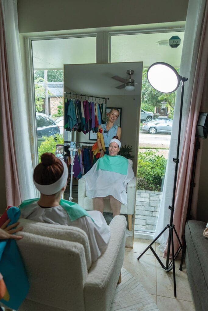 A consultant holds colorful fabric swatches against a person sitting in front of a mirror for a color analysis.