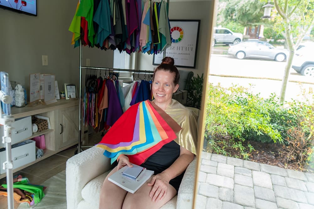 A woman holds colorful fabric swatches during a personal color analysis consultation.