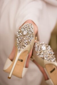 Elegant high heels with gold heels and ornate rhinestone backs, set against a soft, light background.