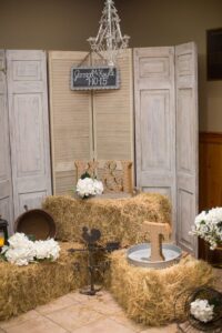 Rustic wedding decor with hay bales, white flowers, marquee letters, chandelier, and a Jarrod & Kayla 7-10-15 sign.