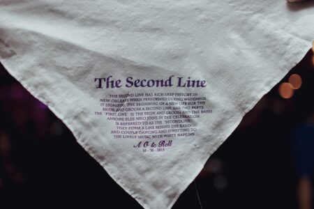 White napkin with purple “The Second Line” title and New Orleans wedding tradition, A & Rell 10-10-2015 at the bottom.