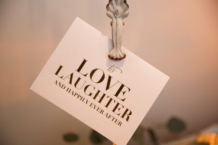 Card on a white holder says, “To love, laughter, and happily ever after” in elegant gold lettering.