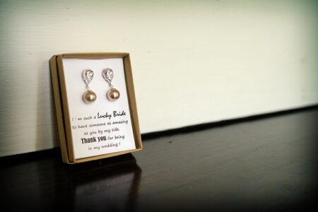 Pearl drop earrings in a box with bridesmaid thank you note, on dark wood—chic New Orleans wedding inspiration.