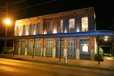 Charming two-story brick building with blue shutters, warmly lit at night—ideal for intimate Gulf South weddings.